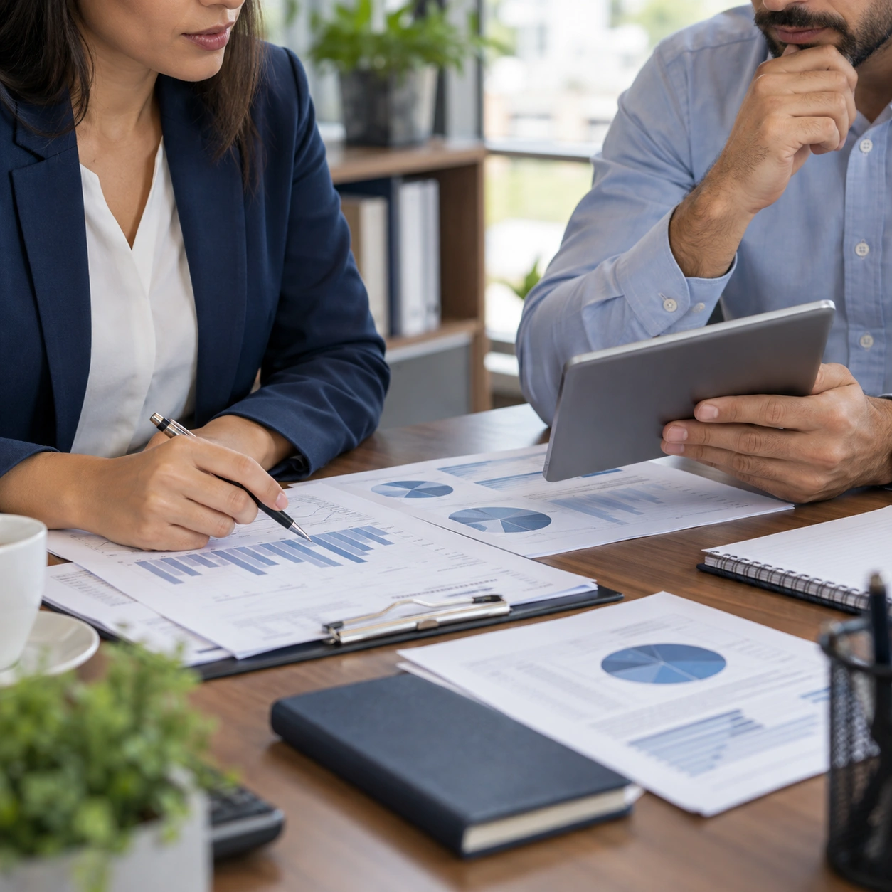 Profissionais analisam relatórios e gráficos em uma mesa de trabalho